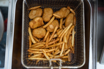 Crispy chicken nuggets with french fries after cooking. Close up