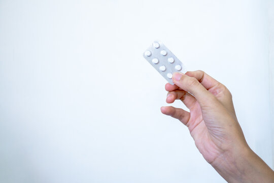 A hand displays a pharmaceutical blister pack containing a two-pill dose of medication, illustrating a moment of personal healthcare, medical choice, and responsibility for one's well-being