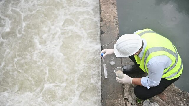 A water resource officer is inspecting water contaminants in a treatment pond