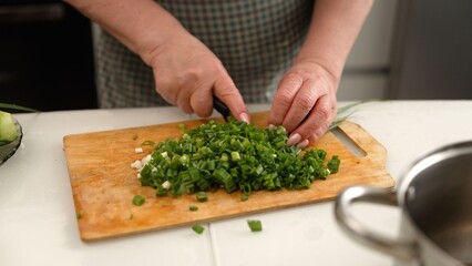 Woman chopping green onions on wooden cutting board