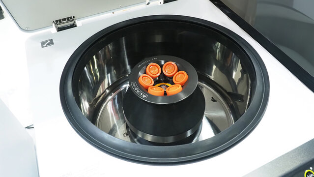 A laboratory centrifuge machine with orange capped sample tubes