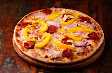 Pizza with chorizo ​​sausage, mozzarella cheese and yellow pepper. Rustic wooden background. Soft focus.	