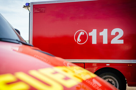 Rotes Feuerwehrfahrzeug mit der Notrufnummer 112, im Vordergrund ein weiteres Einsatzfahrzeug unscharf. Symbolisiert Notruf, Einsatzkr&auml;fte, Rettungsdienst und &ouml;ffentliche Sicherheit.