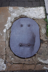 The marks on the iron plate on the floor look like facial expressions.