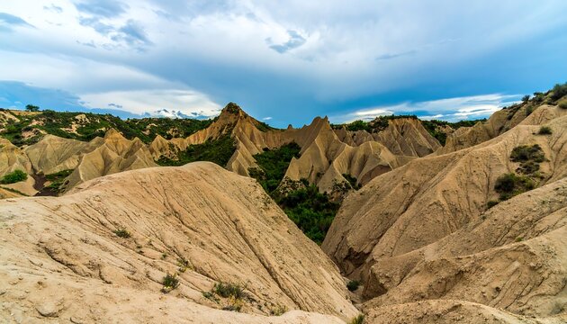 Eroded earth hills under dramatic sky