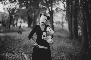 Spooky Halloween scene with mask, teddy bear, and knife