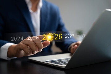 Businessman pointing at digital target icon on 2026, planning business strategy and future growth with technology concept on laptop screen. leadership and upcoming opportunities.