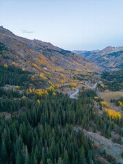 Obraz premium Aerial view of winding road through autumn forest.