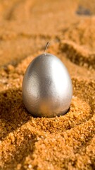 Silver egg candle on golden sand