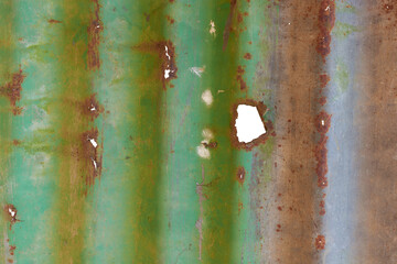 heavily weathered corrugated metal sheet with holes isolated white background, textured surface...