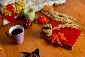 A warm arrangement showcases a cup of coffee, freshly baked cookies, and autumn leaves around a...