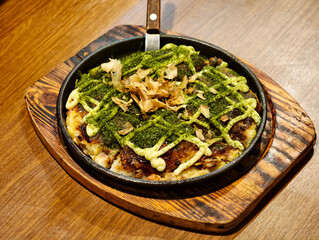 okonomiyaki in a pan topped with dried seaweed and bonito flakes. Japanese food