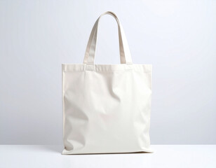 A plain, off-white reusable tote bag stands upright on a white surface against a light gray backdrop.