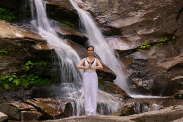 woman performing slow tai chi movements near a waterfall and river at sunset capturing harmony balance and fitness in nature
