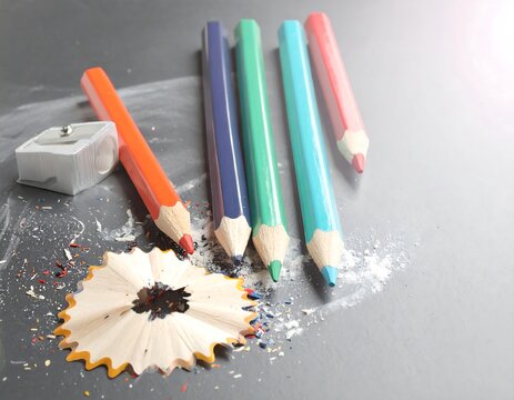 Colorful pencils and sharpener on a dark surface