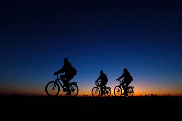 Silhouettes of three cyclists at twilight