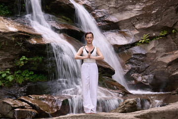 woman performing slow tai chi movements near a waterfall and river at sunset capturing harmony balance and fitness in nature