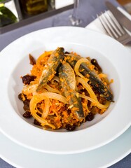 Bowl of cooked fish, onions, and raisins