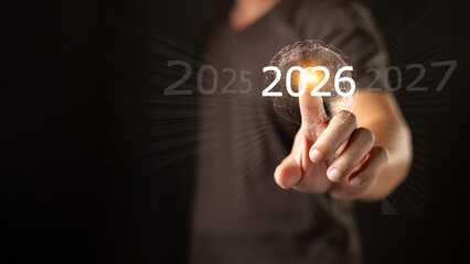 A person touches a glowing digital interface highlighting the year 2026 between 2025 and 2027, symbolizing future planning, technology, progress, and strategic vision for upcoming opportunities.