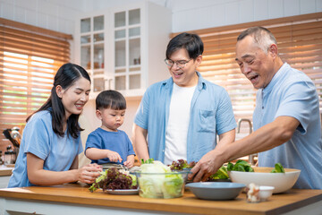 : Happy multi-generational Asian family preparing salad together in the kitchen. A young child participates by holding a tomato, highlighting warmth, healthy lifestyle, and family bonding.