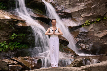 woman performing slow tai chi movements near a waterfall and river at sunset capturing harmony balance and fitness in nature