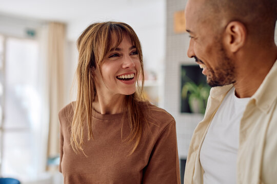 Cheerful young multi-ethnic couple sharing a laugh together, enjoying a moment of happiness and connection in their modern home