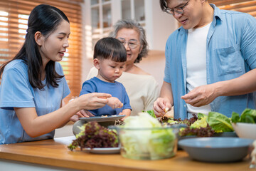 Asian multigenerational family enjoying mealtime in the kitchen with fresh vegetables. Grandmother...