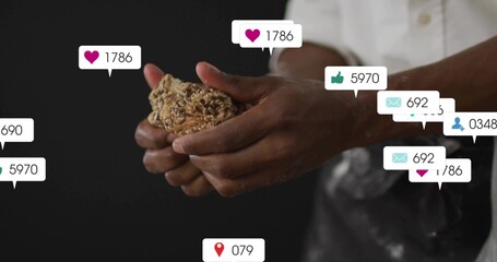 Holding oat and seed cluster, male wearing apron standing in studio kitchen with notification icons