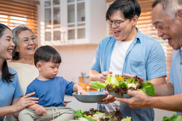 Asian multigenerational family enjoying mealtime in the kitchen with fresh vegetables. Grandmother warmly hugs the toddler while parents serve food, highlighting love, care, and healthy living.