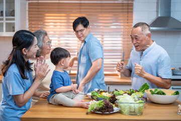 Asian family spending quality time together in the kitchen, preparing healthy meals with fresh...