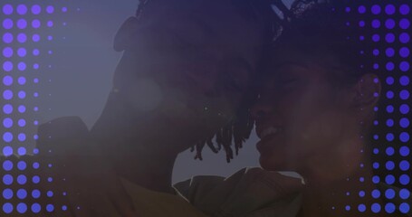 Leaning heads together couple wearing light jacket and t-shirt under clear sky, purple dot overlay