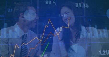 Colleagues in formal attire studying financial charts on transparent display in boardroom