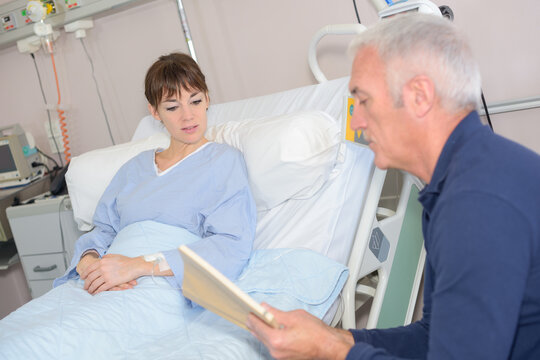woman laying on a hospital bed while dad is reading