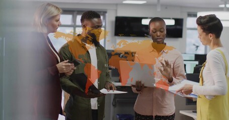 Collaborating team in business wear reviewing laptop and documents around map overlay in office