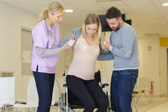 smiling nurse assisting woman to get up from wheelchair - Powered by Adobe