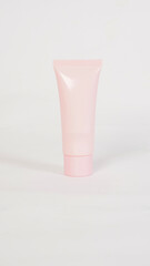 A plain pastel pink cosmetic tube on a white background