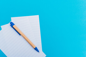A blank notebook and pencil for writing notes and lists on an empty page with a blue background