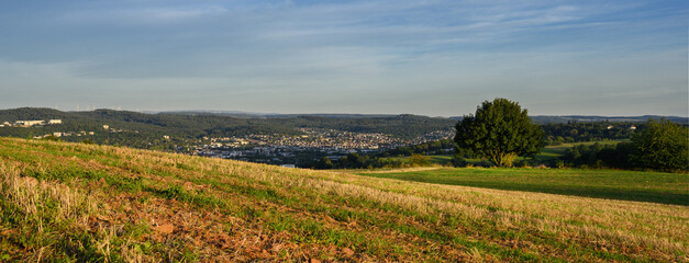 Obraz premium Weiter Blick über Felder zu Bergen mit Wald und Blick auf die Stadt