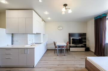 well-lit studio apartment featuring a modern kitchen, dining area, and entertainment center with a TV