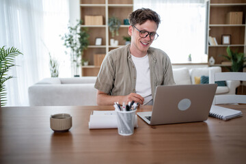 Young man working from home on laptop and smiling