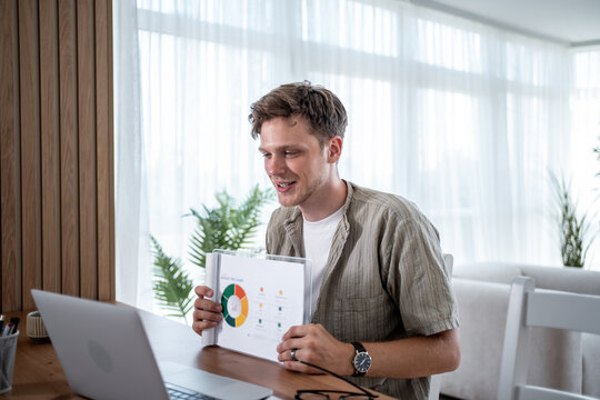 Young businessman showing charts and graphs during a video call meeting at home office