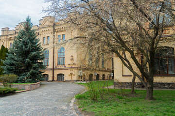 Kyiv. Kyiv Polytechnic Institute. Large, yellow brick building with detailed architectural features, numerous windows, and surrounding green lawns and trees on a cloudy day
