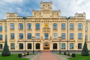 Kyiv. Kyiv Polytechnic Institute. Large, yellow brick building with detailed architectural features, numerous windows, and surrounding green lawns and trees on a cloudy day
