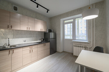 bright, modern kitchen features light wood cabinets, gray countertops, and stainless steel...