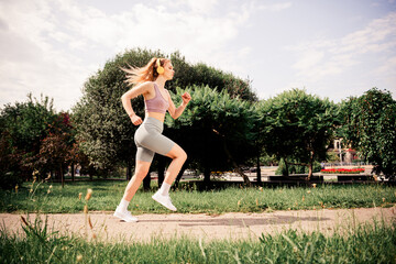 Athletic woman jogging in a park wearing stylish activewear, enjoying sunny weather and practicing...