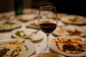 Naklejka premium A glass of red wine sits near many empty plates.