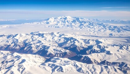 Fototapeta premium A high-angle shot showcasing snow-covered mountain ranges under a clear, blue sky with wispy clouds. 