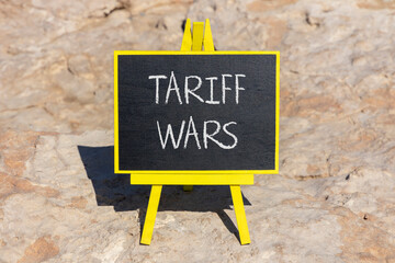 Trade tariff wars symbol. Concept word Tariff wars on beautiful black blackboard. Beautiful stone...