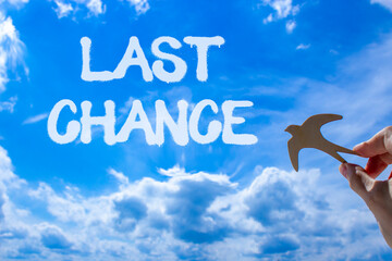 Last chance symbol. Concept word Last chance on beautiful blue sky. Businessman's hand with wooden...