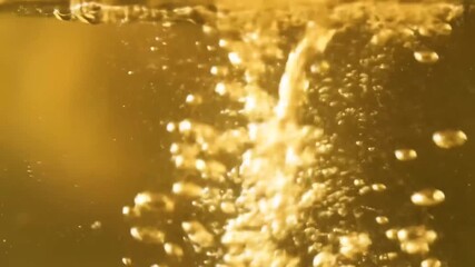 Bubbles rise in golden liquid, blurring details in a chaotic cascade, suggesting carbonation or boiling, creating an abstract effect